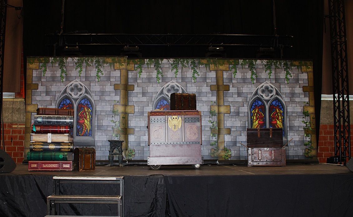 Décor du spectacle avec château, vitraux, grimoires et coffres magiques